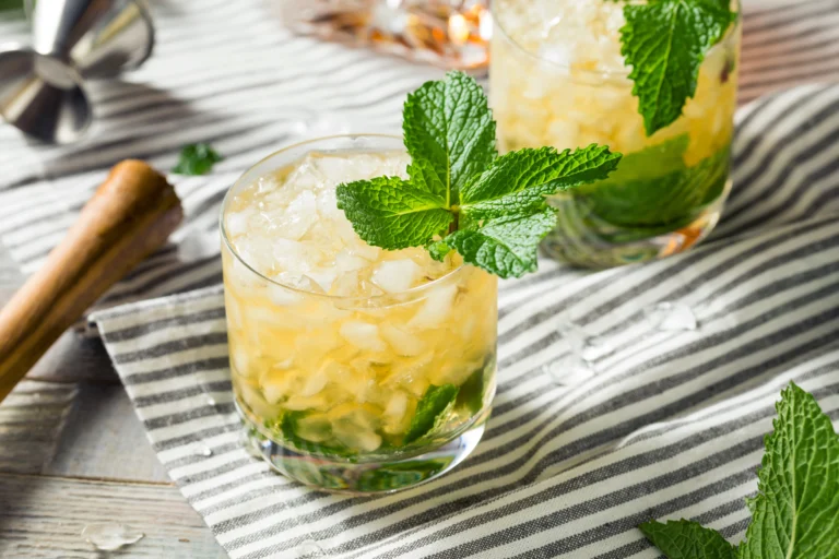 Mint julep cocktail on a striped cloth with fresh mint garnish.
